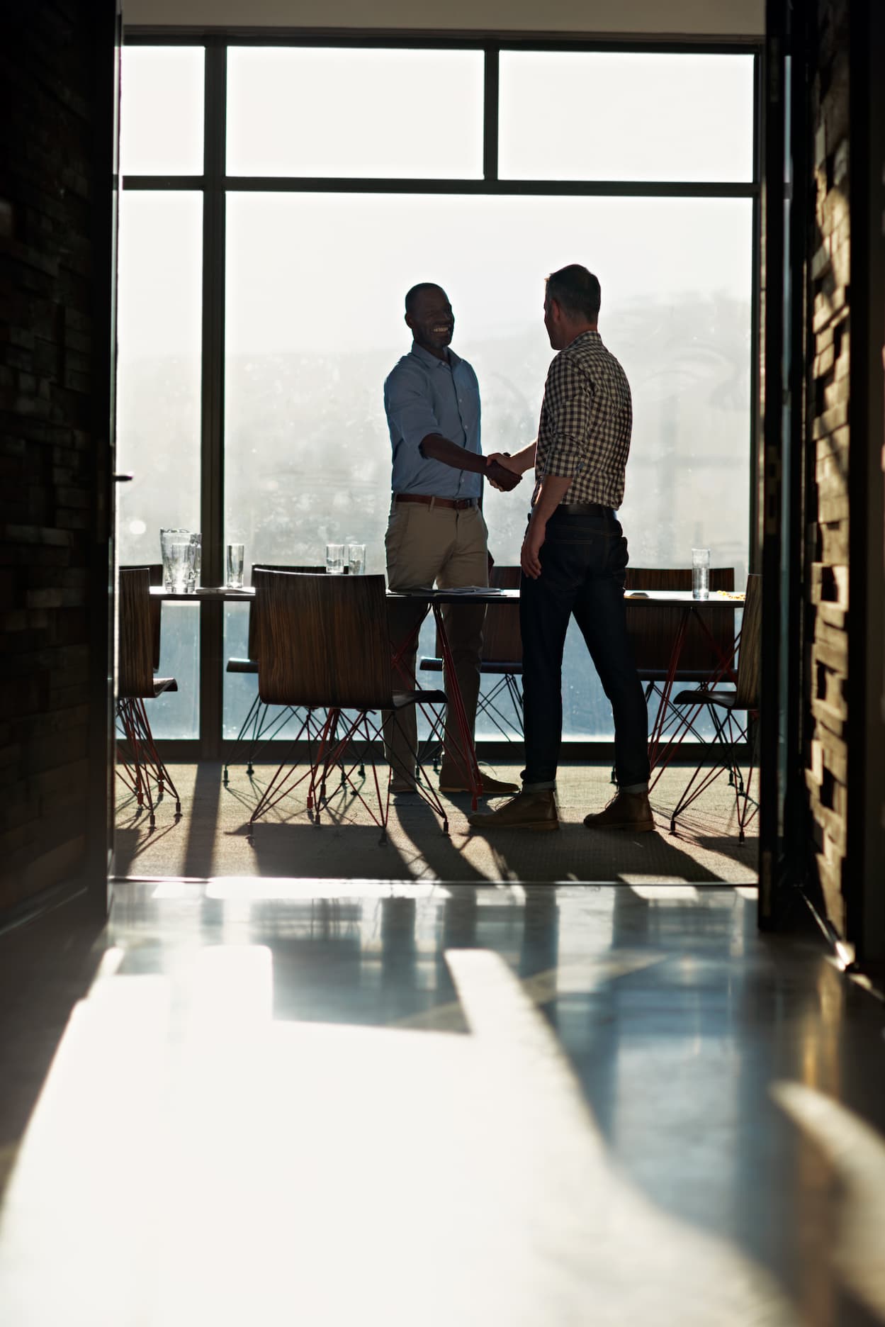 2 businessmen shaking hands in light filled office