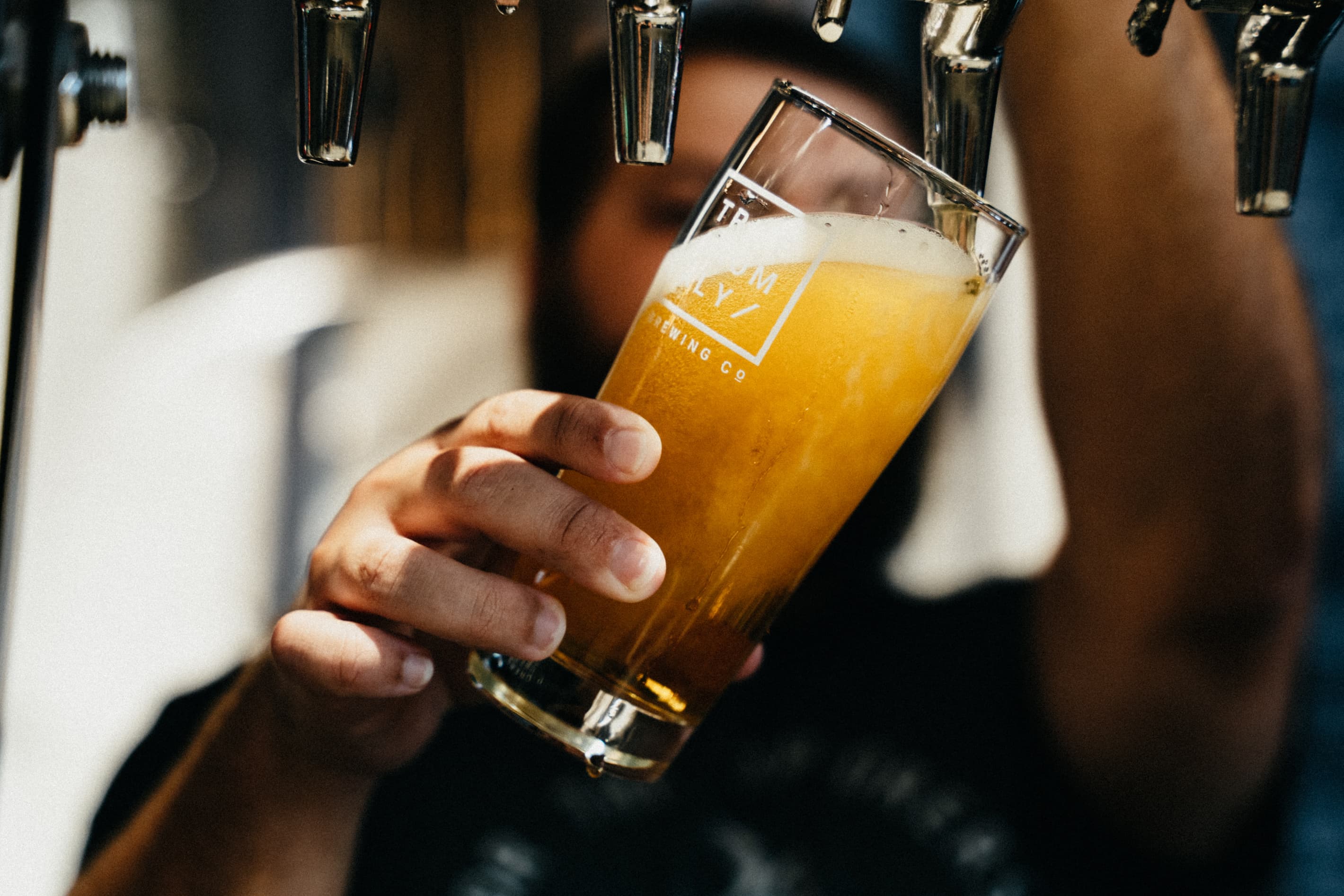 Close up shot of hands pulling a pint of cloudy ale