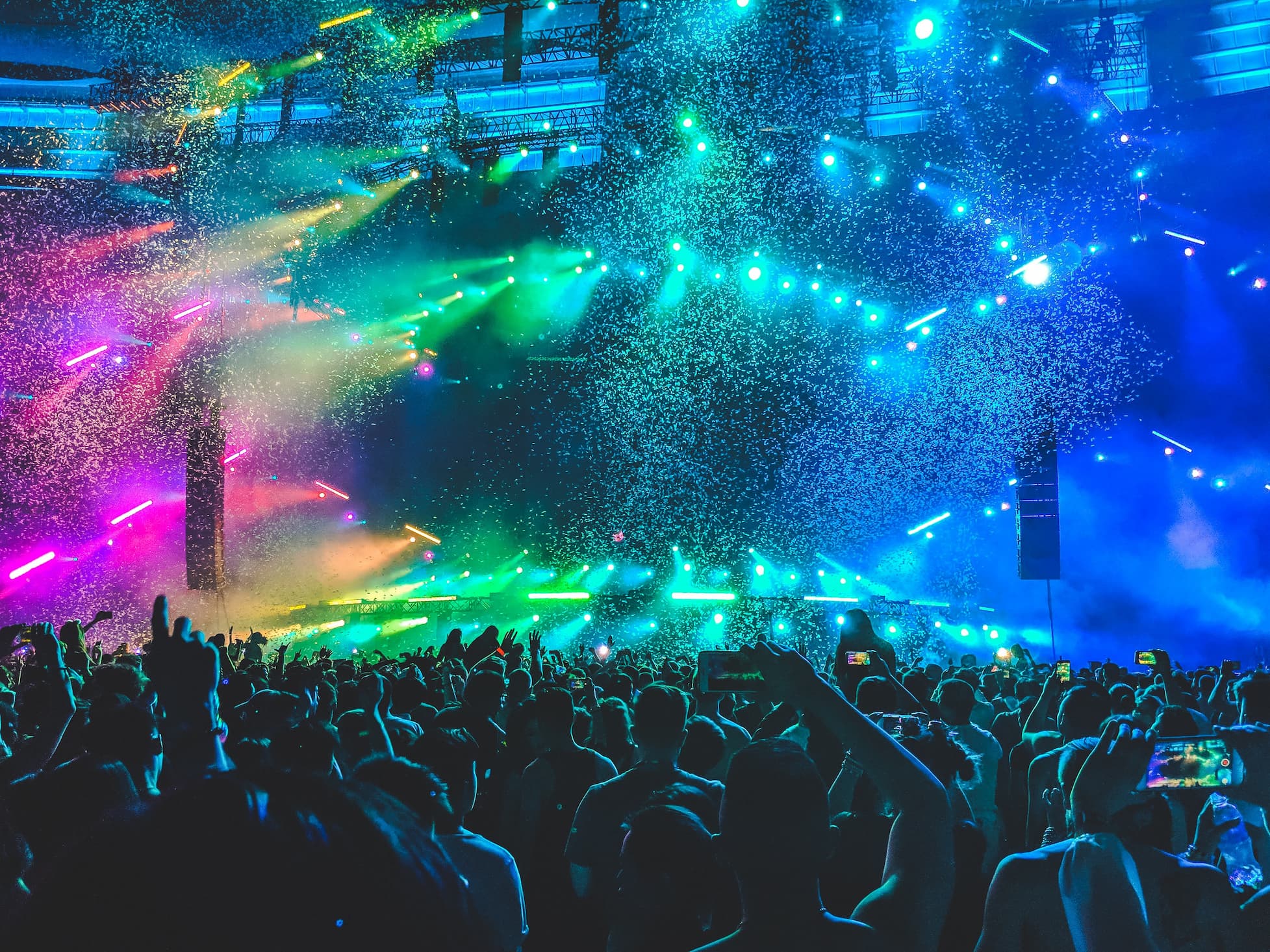 Rainbow lighting illuminating crowd at large live event