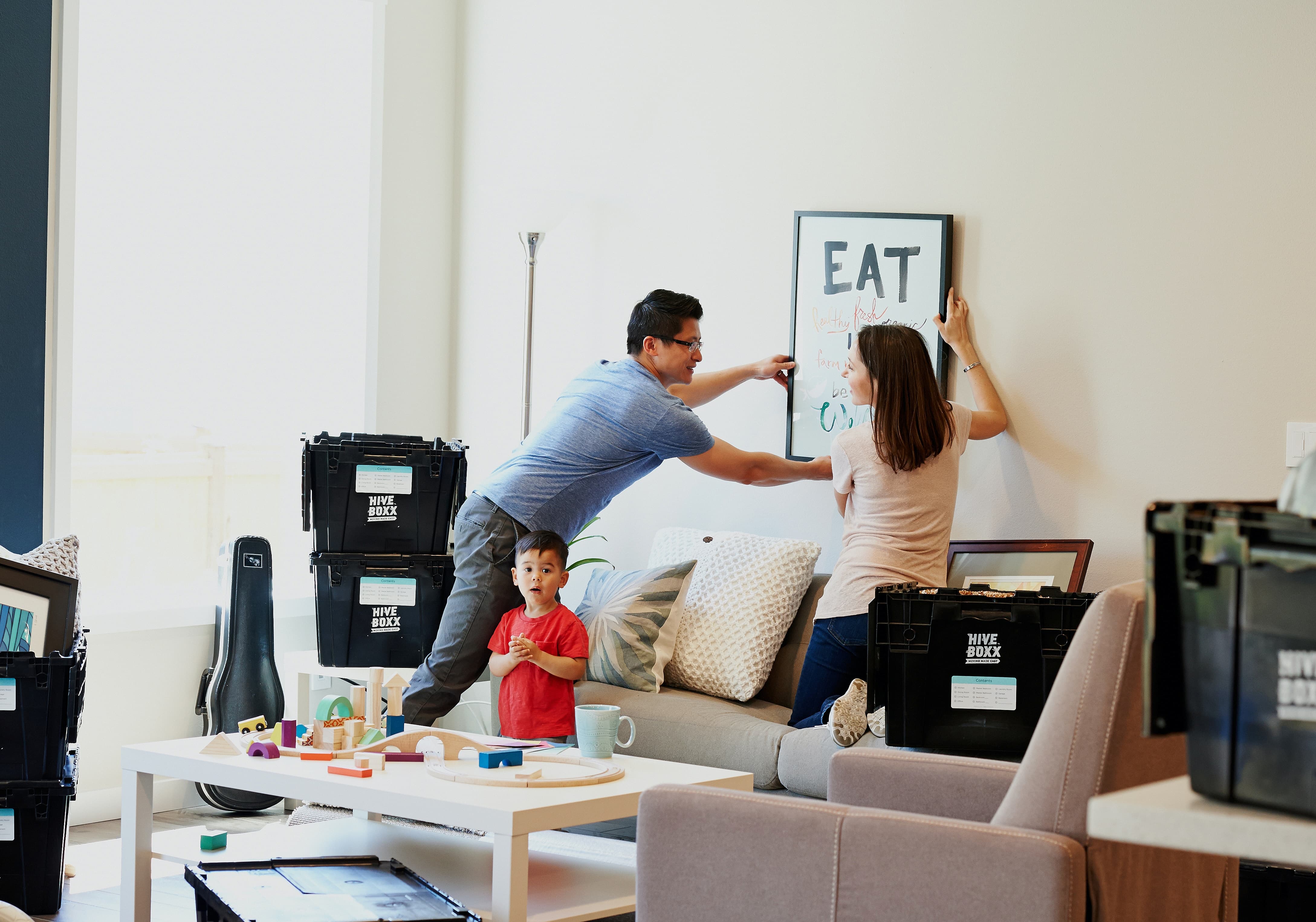 Family putting up framed picture on wall in new home
