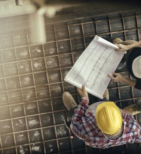 A female architect discusses a plan with two construction workers