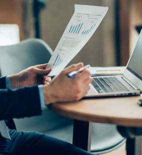 A financial accountant reviews a page of figures while using his laptop