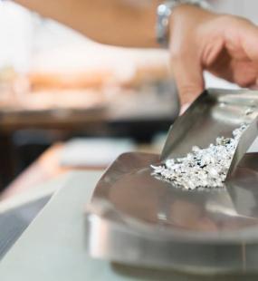 A jeweller pours particles of silver onto a scale