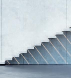 A modern flight of stairs with no riser or banister runs up the side of a building to a platform and casts shadows on the wall below