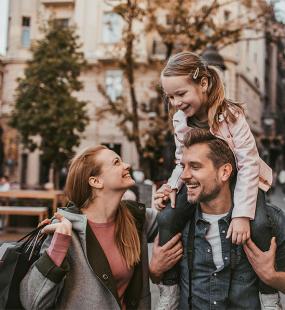 parents with child laughing and smiling, piggy back