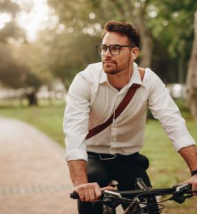 a man cycling to work through a park - flexible benefits covid-19 Howden