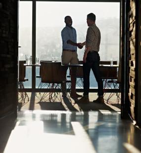 2 businessmen shaking hands in light filled office