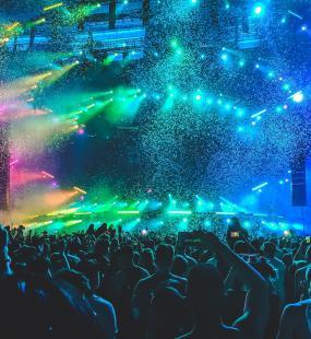 Rainbow lighting illuminating crowd at large live event