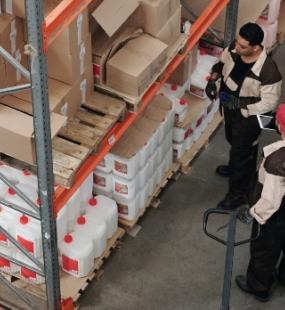 personnel in a warehouse looking at shelved products