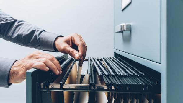 Hands move files in a filing cabinet