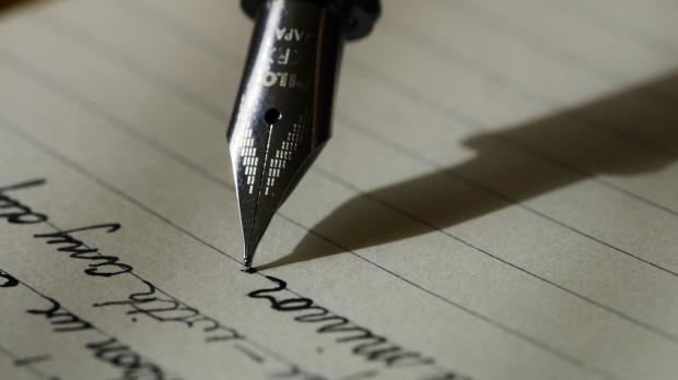A fountain pen writing on a sheet of lined paper