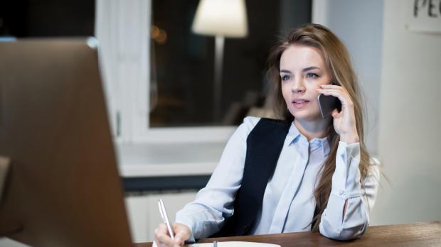 Female solicitor at her desk looking at her laptop whilst on the phone