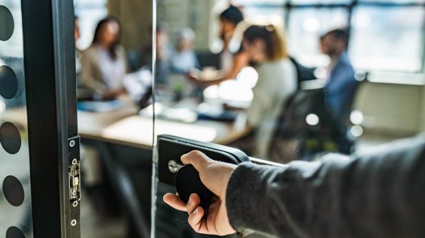 Opening clear door through to colleagues sitting around a table