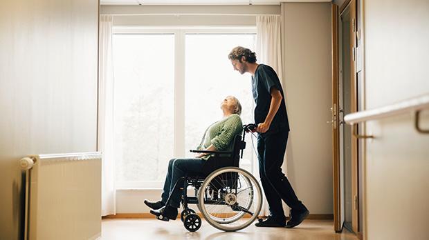 Elderly person in a wheelchair being pushed by a carer