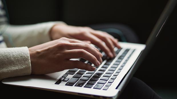 hands typing at a laptop keyboard